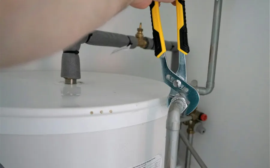 Gasfíter apretando la conexión de agua de un calentador
